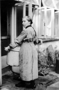 876772 Afbeelding van een Zuster Augustines, met een gamel in handen op de buitenplaats bij de gaarkeuken, die ...